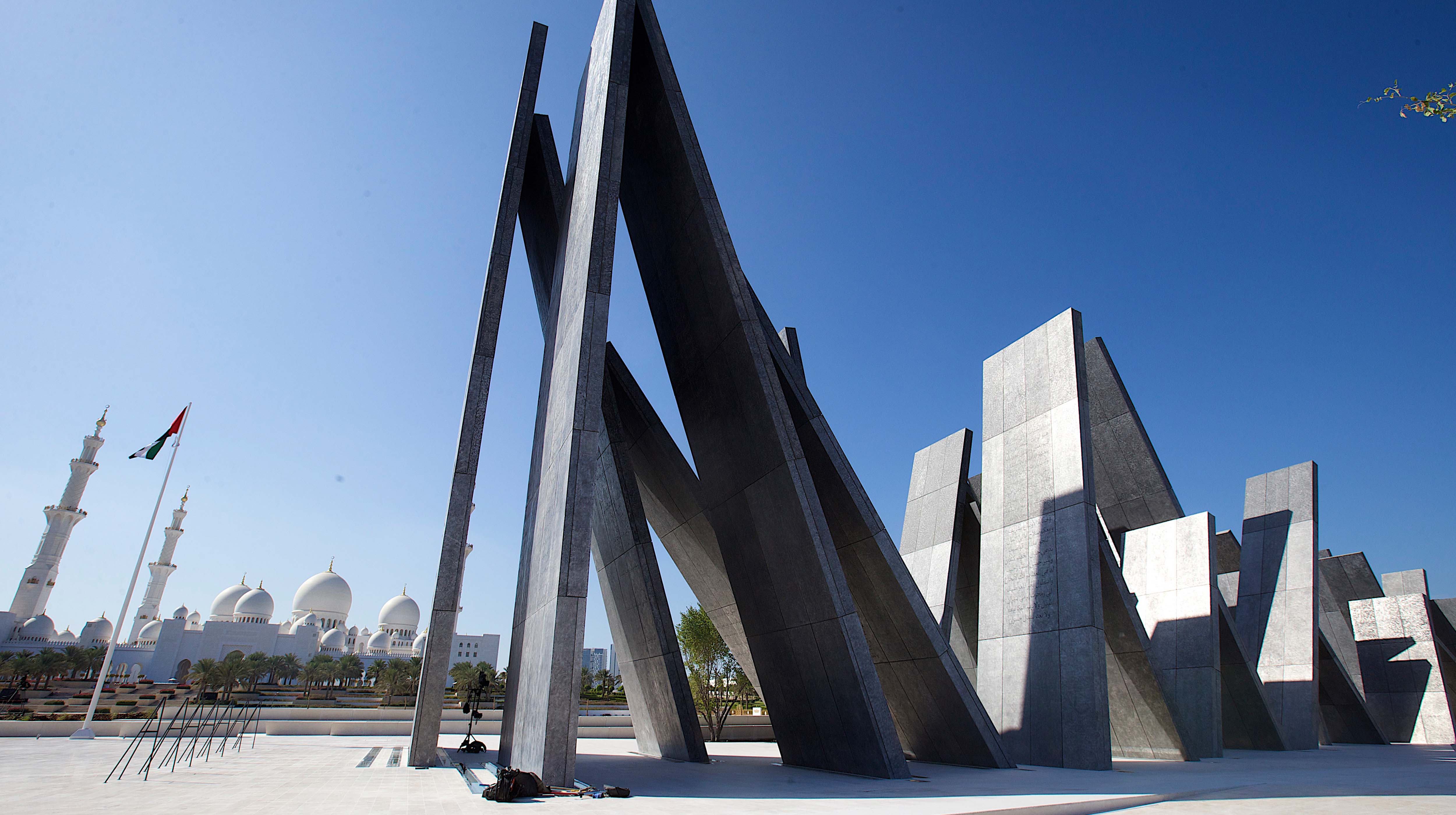 Vista del Memoriale dei Martiri Wahat Al Karama ad Abu Dhabi con sculture in acciaio inclinato e sullo sfondo le cupole bianche e i minareti della Moschea Sheikh Zayed